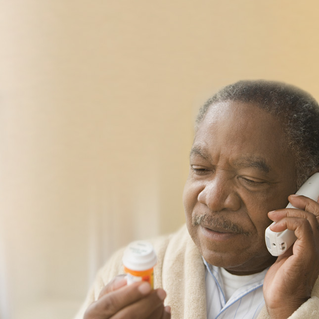 man on the phone with a prescription bottle in hand