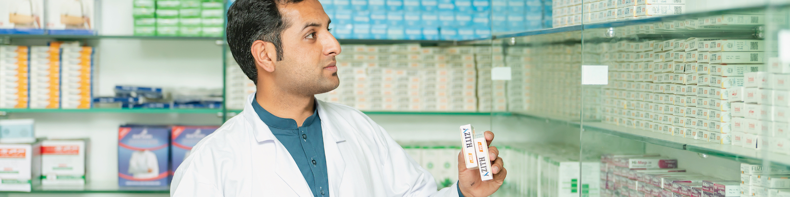 man in lab coat stocking medicine in a pharmacy