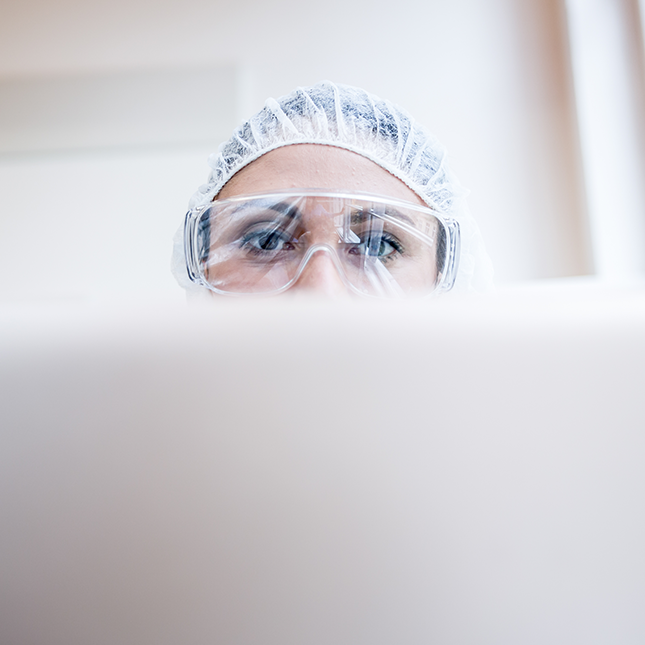 Woman scientist working in a lab with goggles and hair net on